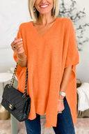 Woman wearing an orange oversized sweater holding a black handbag indoors.