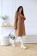 Woman wearing a beige trench coat in an indoor setting