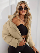 Woman wearing a beige puffer jacket and black top against a white background