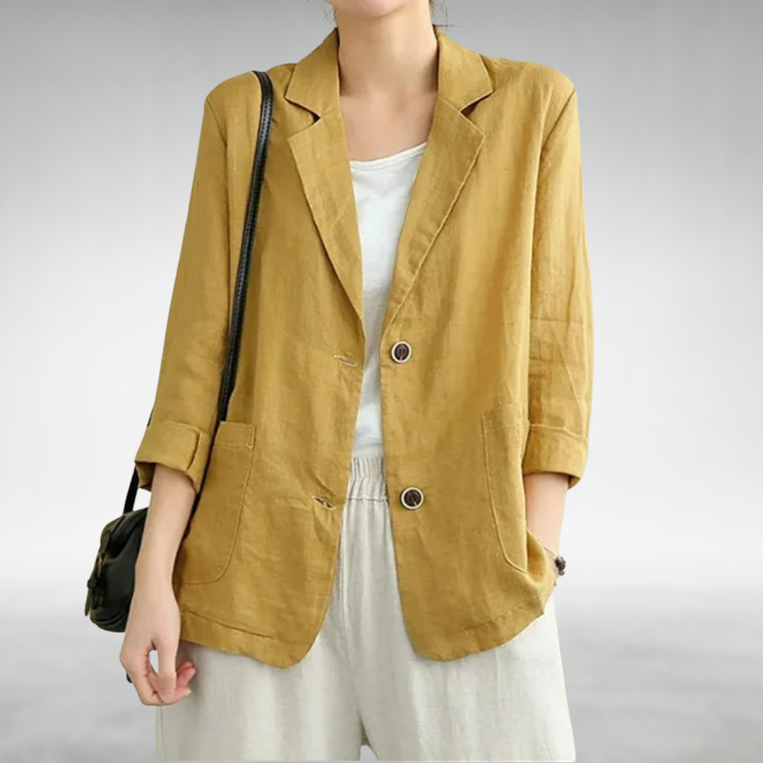 Person wearing a mustard yellow blazer over a white top on a plain background