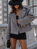 Person wearing a gray coat and black hat in an urban setting