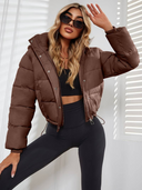 Woman wearing a brown puffer jacket and black leggings posing against a white background