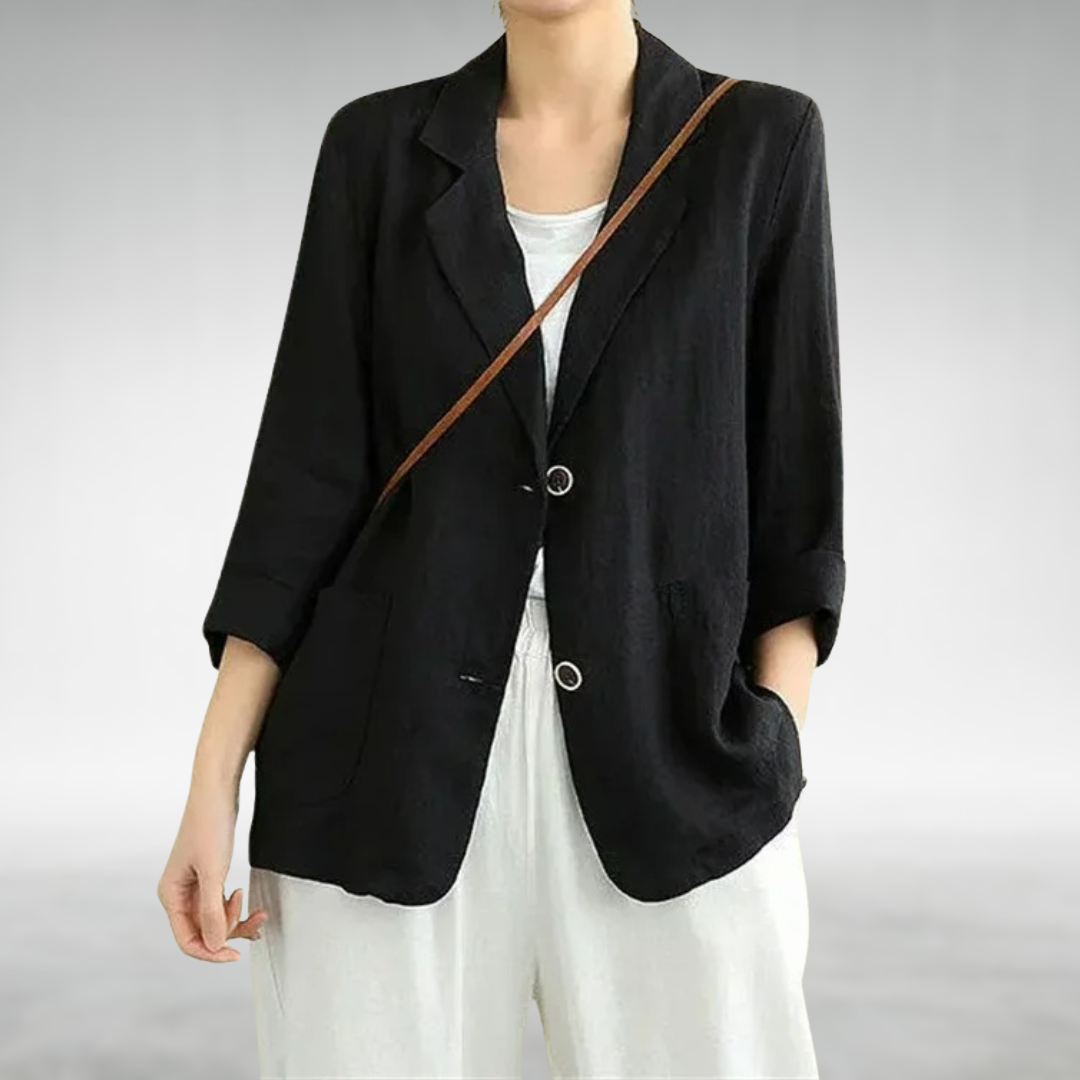 Person wearing a black blazer over a white top on a plain background