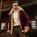 Man wearing a maroon shearling jacket and sunglasses outdoors.
