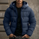 Man wearing a blue puffer jacket standing against a neutral background