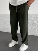 Person wearing dark  green ribbed pants and white sneakers against a light gray wall.
