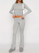 Person wearing a gray long-sleeve top and pants on a white background