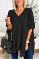 Woman wearing a black oversized sweater holding a black handbag indoors.