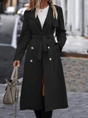 Person wearing a black coat with white buttons, holding a gray bag on a city street.
