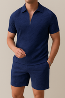 Man wearing a navy blue textured polo shirt and shorts on a beige background