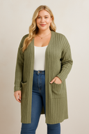 Woman wearing an olive green cardigan over a white top and blue jeans on a beige background