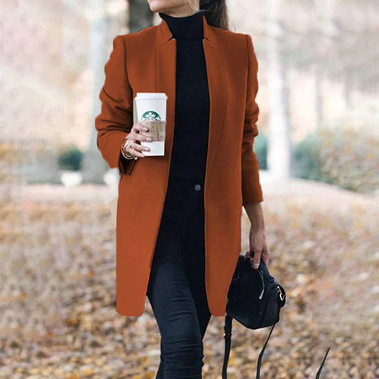 Person wearing a brown coat holding a cup outdoors.