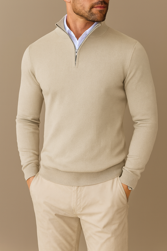 Man wearing a beige sweater and pants against a brown background