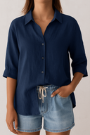 Person wearing a navy blue shirt and denim shorts on a plain background
