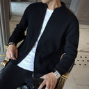 Person wearing a black cardigan over a white shirt, sitting on a decorative chair.