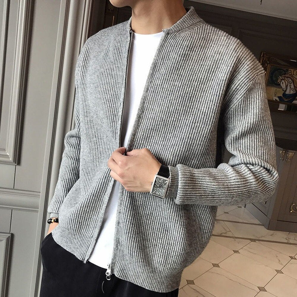 Person wearing a gray textured cardigan over a white shirt in an indoor setting.
