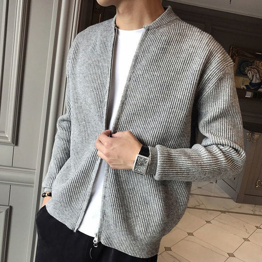 Person wearing a gray textured cardigan over a white shirt in an indoor setting.