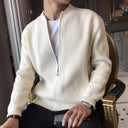 Person wearing a cream-colored sweater over a white shirt, sitting on a chair.