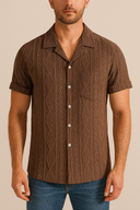 Man wearing a brown patterned shirt with short sleeves against a beige background