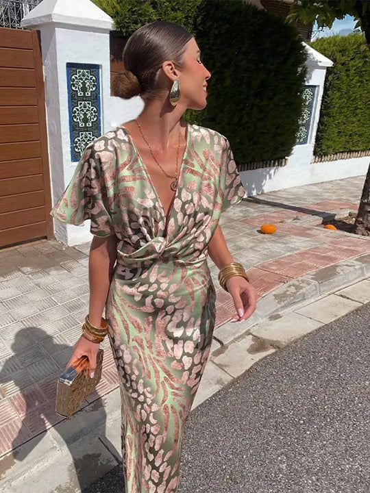 Woman in a patterned dress walking outdoors on a sunny day.