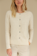 Woman wearing a beige cardigan with buttons on a beige background