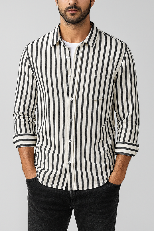 Man wearing a black and white striped shirt with rolled-up sleeves on a gray background