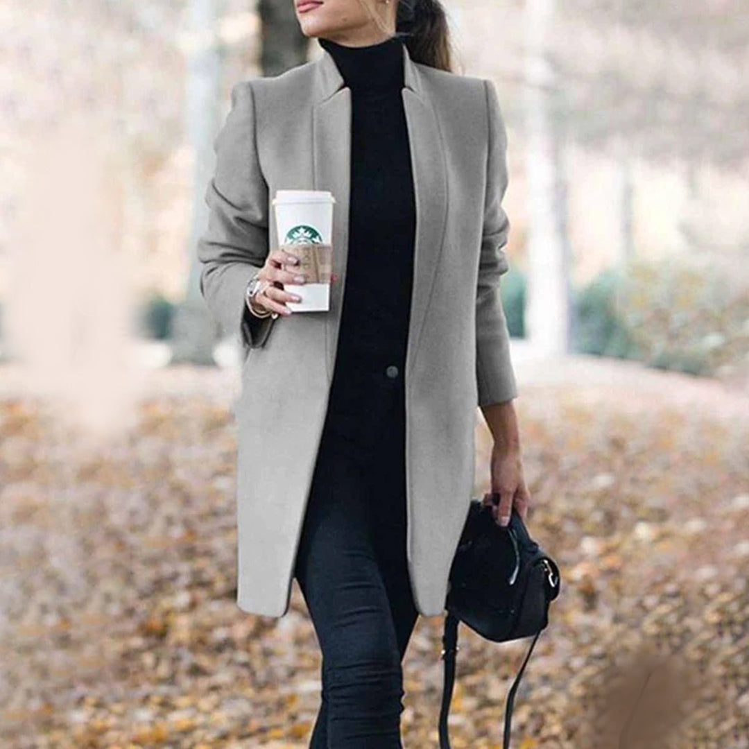Woman in a gray coat holding a cup outdoors