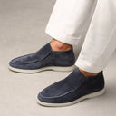 Navy loafers worn with white pants on a neutral background