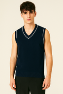 Man wearing a navy blue sleeveless sweater with white trim on a beige background