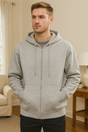 Man wearing a gray hoodie in a room with a lamp and chair.