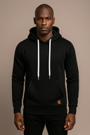 Man wearing a black hoodie with white drawstrings on a beige background