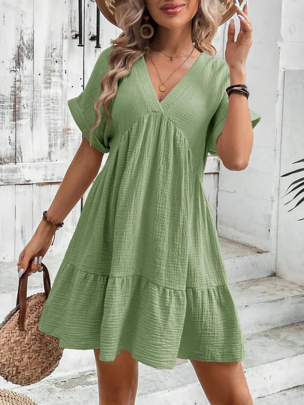 Woman wearing a green dress with a white wooden background