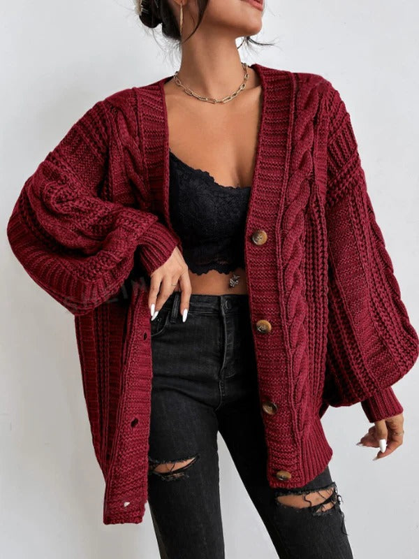 Person wearing a red knitted cardigan over a black top and jeans on a white background