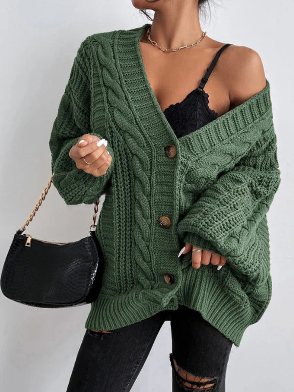 Person wearing a green knitted cardigan with a plain background