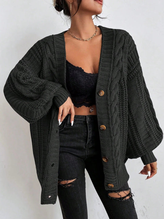 Person wearing a dark green cardigan over a black top and jeans on a white background