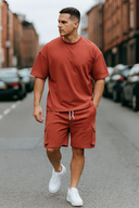Man wearing a red outfit with white sneakers on a street.