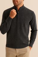 Man wearing a dark gray sweater with a zipper on a beige background