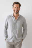 Man wearing a light gray button-up shirt against a plain background
