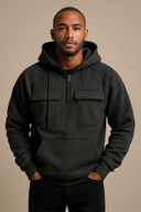 Man wearing a dark gray hoodie with front pockets against a beige background