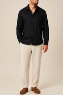 Person wearing A longsleeve men's linen set, consisting of a black shirt and beige pants, displayed on  plain background