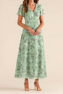 Woman wearing a green floral dress on a beige background