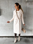 Woman wearing a white coat against a gray concrete wall