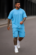 Man wearing a blue outfit with tattoos walking on a street.
