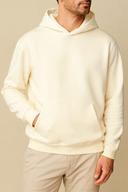 Person wearing a cream hoodie against a beige background