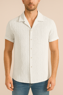 Man wearing a white short-sleeve shirt with a subtle pattern on a beige background