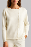 Woman wearing a cream-colored cardigan against a gray background