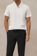 Person wearing a white short-sleeve shirt and black pants on a beige background