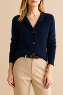 Person wearing a navy blue cardigan with beige pants on a neutral background