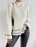 Person wearing a white ribbed sweater with black trim against a white background