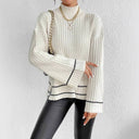 Person wearing a white ribbed sweater with black accents against a white background